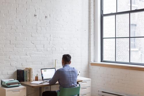 man sitting on a desk with his laptop